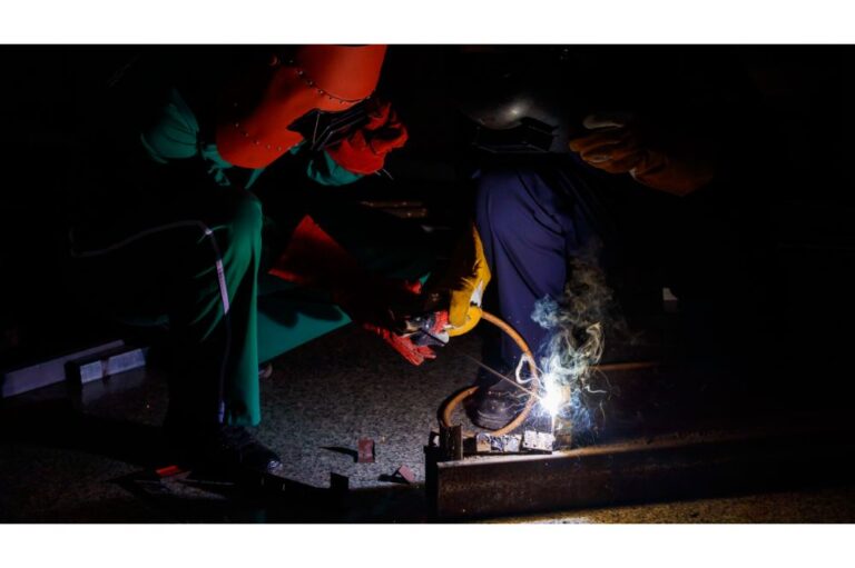 welder wearing safety outfits with mechanic jumpsuits, gloves, boots, and welding helmets